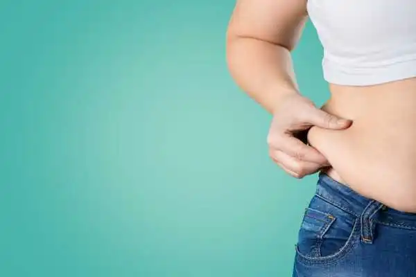 Image of woman pinching her love handles to show weight gain Greenhead