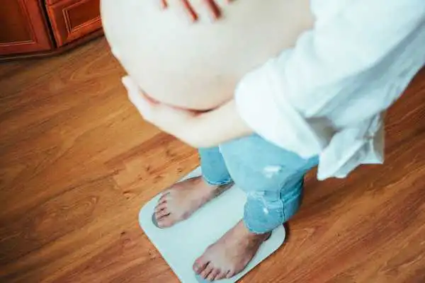 Image of woman weighing herself and experiencing weight gain through pregnancy Greenhead